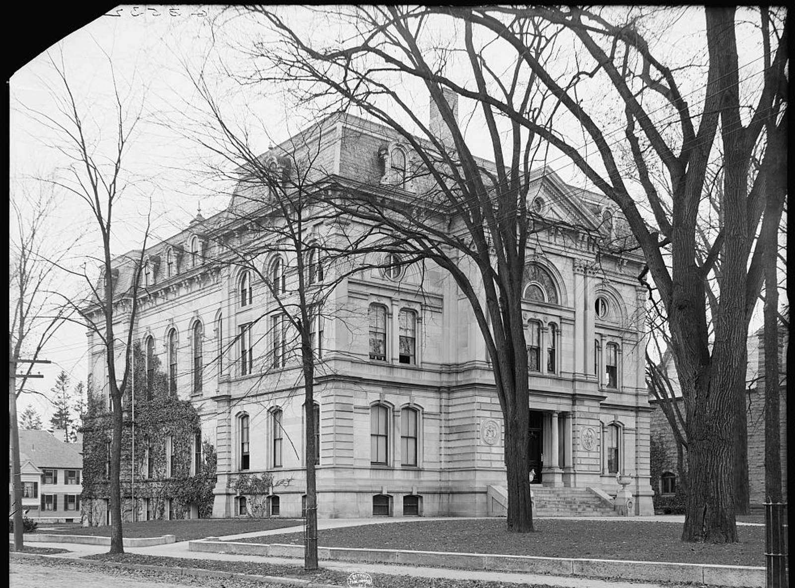 A three-story stone courthouse behind bare trees.